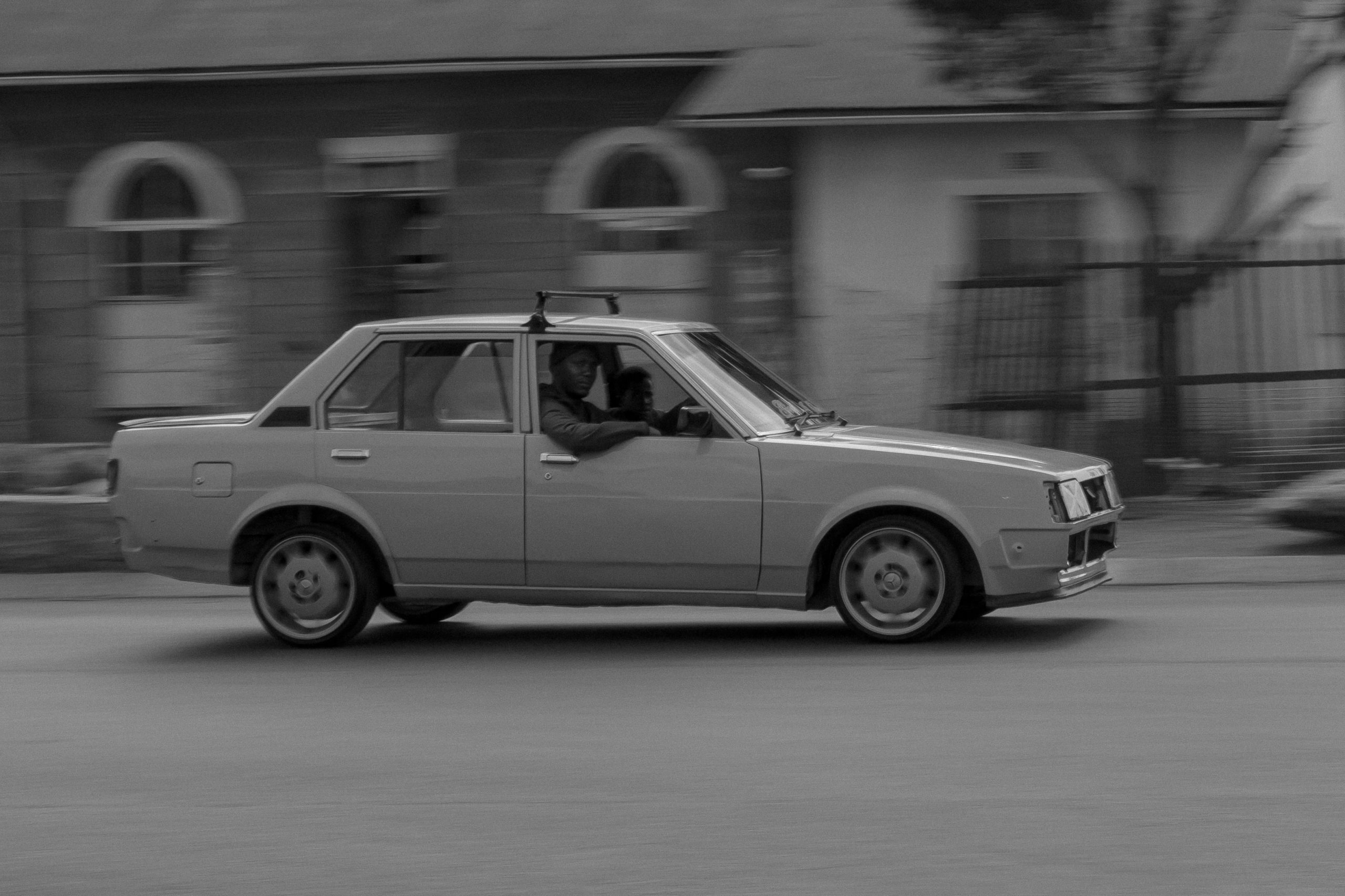 Image of car driving past with driver looking directly at the camera